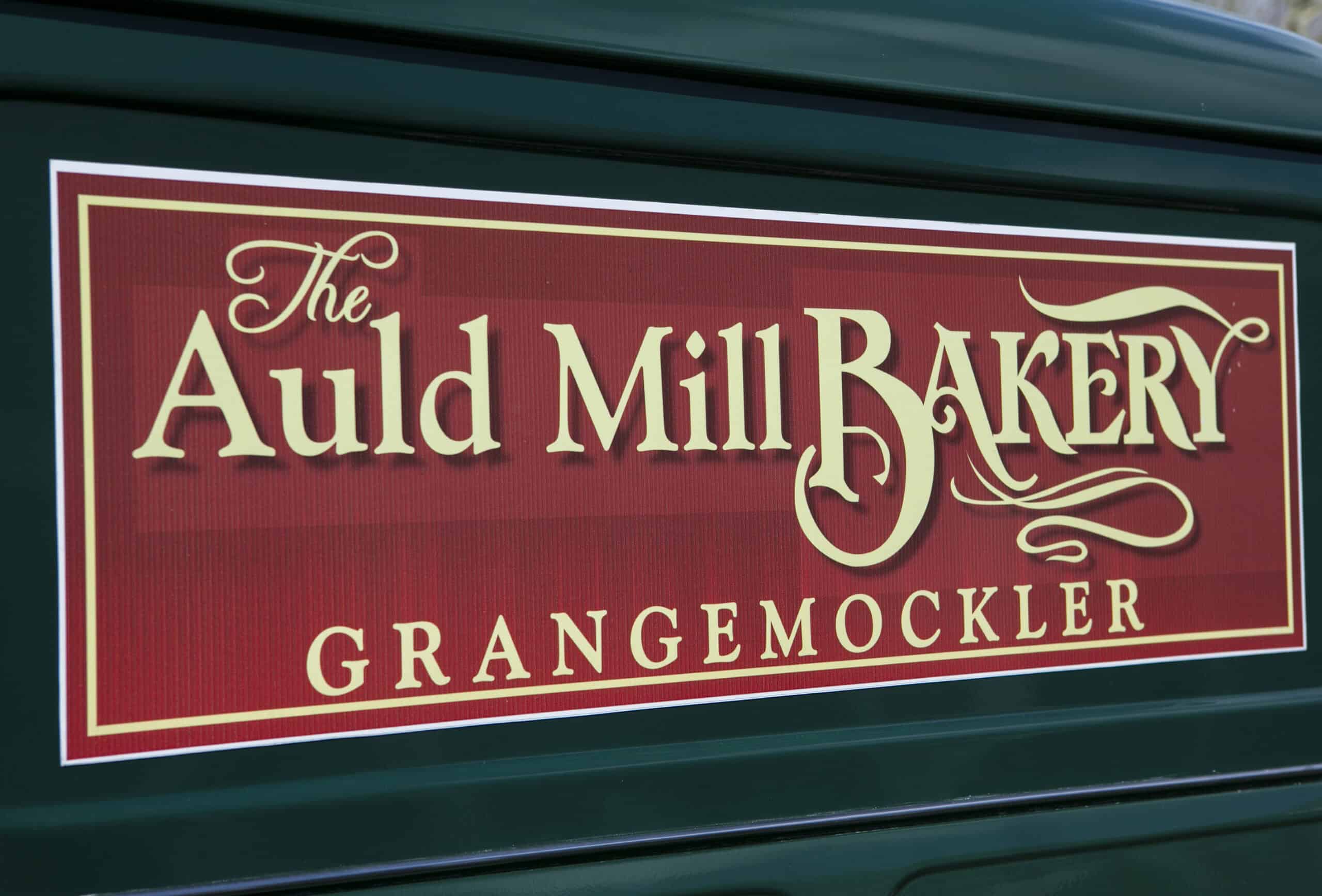 The Auld Mill Bakery sign on a green background, showcasing bakery branding in Grange, Mockler.